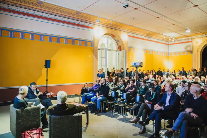 Raum mit vielen Menschen auf Stühlen