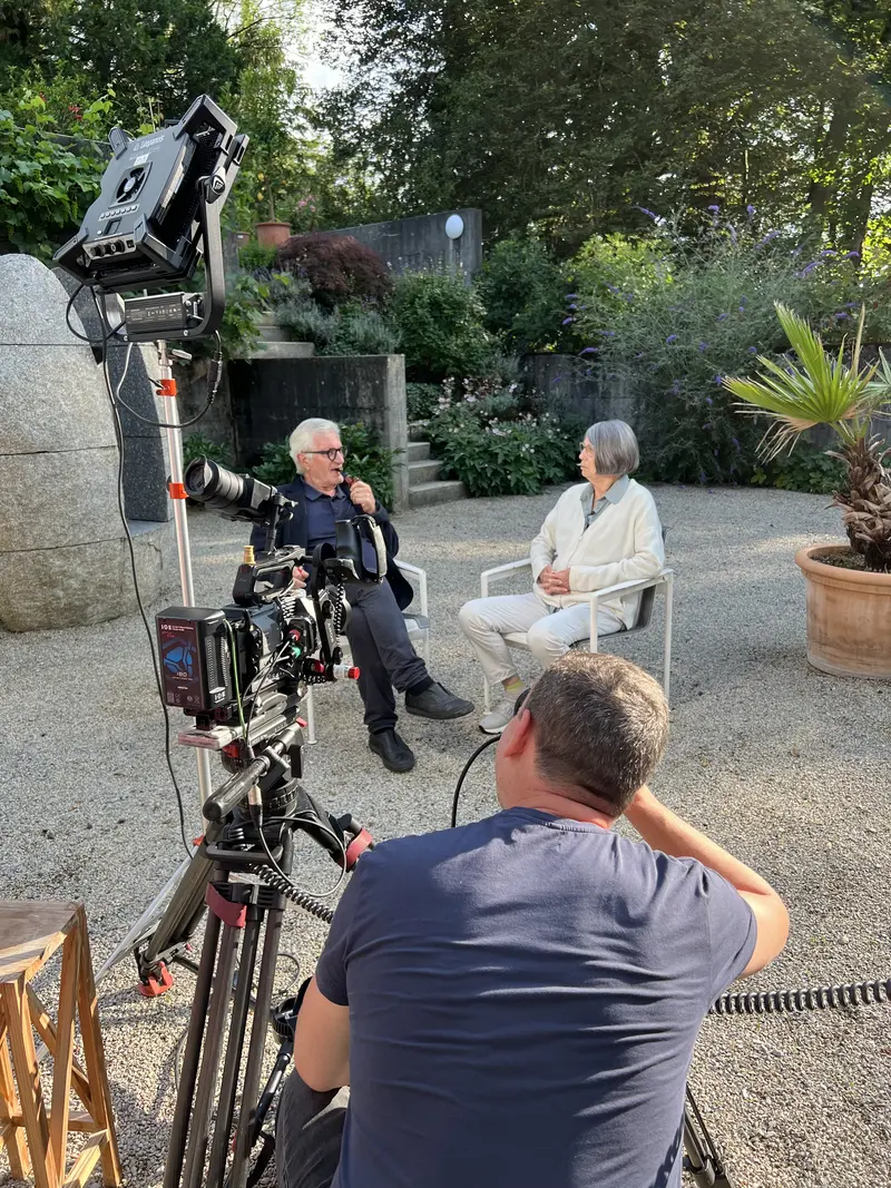 zwei Personen in einem Garten vor einer Kamera