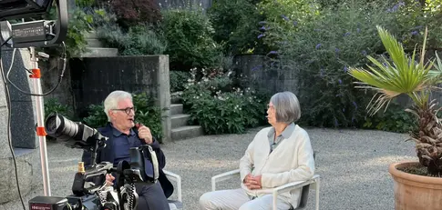 zwei Personen in einem Garten vor einer Kamera