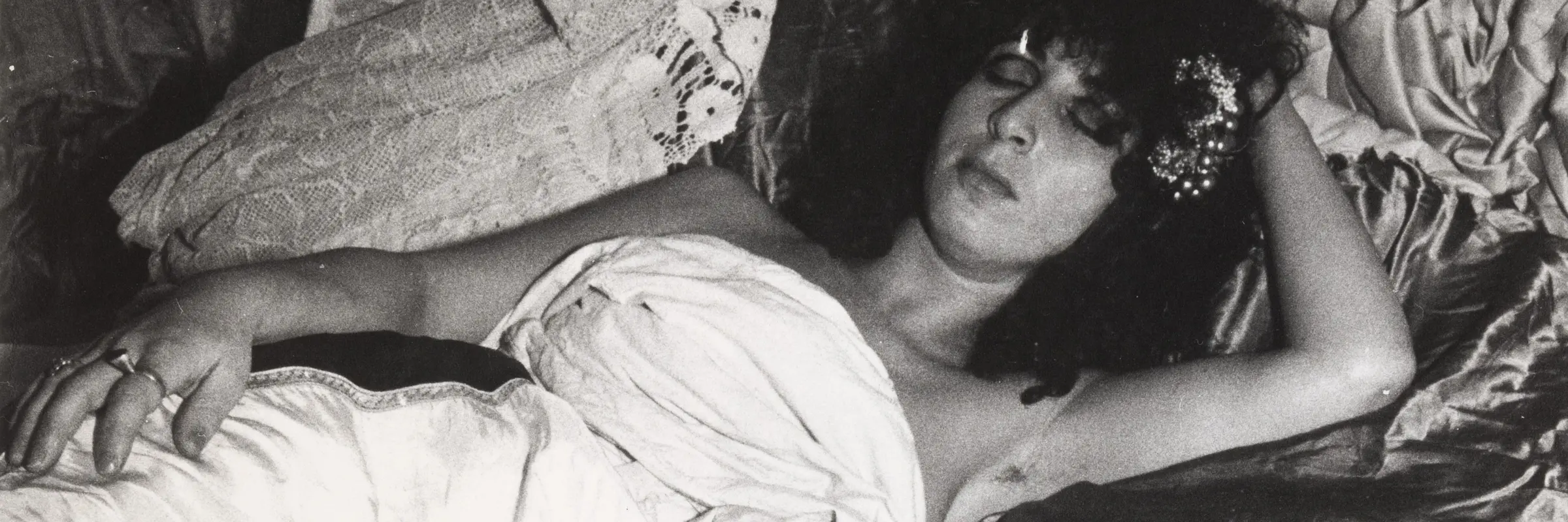 Frau liegt in einem Bett, vorne eine Champagnerflasche
