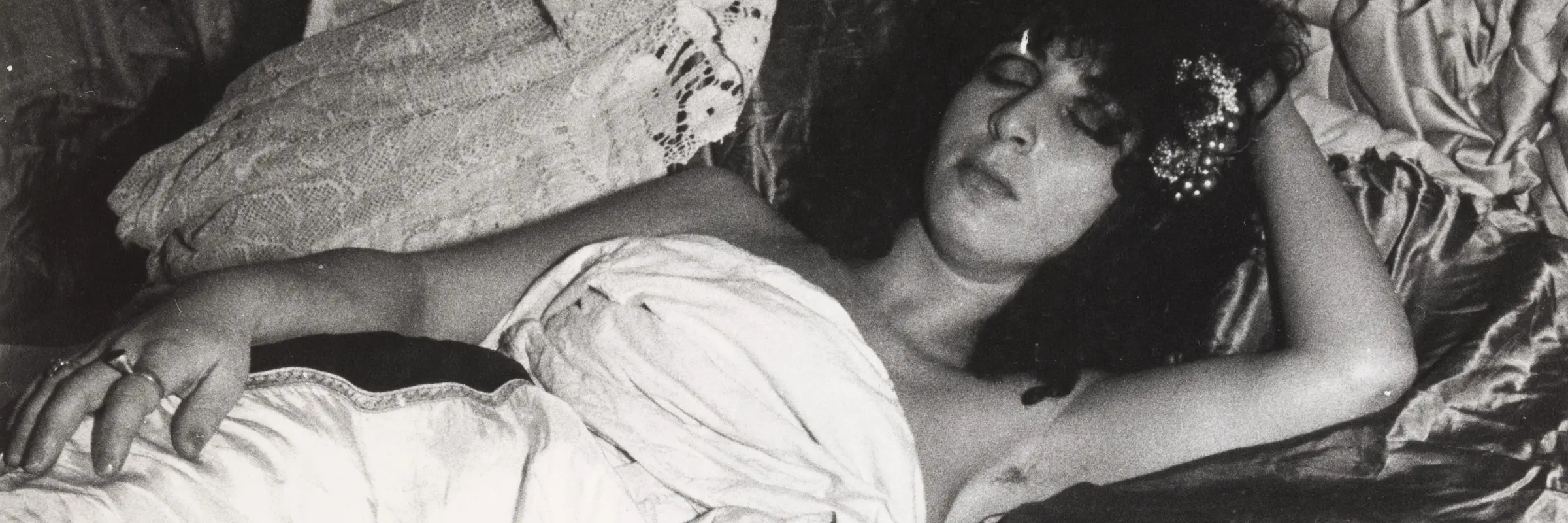 Frau liegt in einem Bett, vorne eine Champagnerflasche