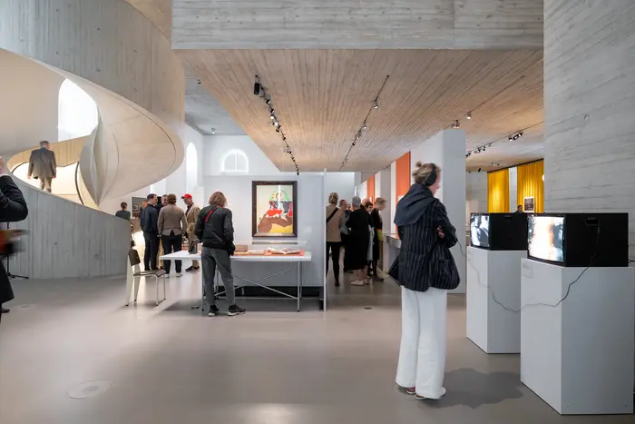 Menschen in einem Ausstellungsraum mit kleinen Fernsehgeräten.