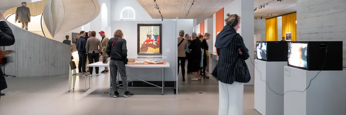Menschen in einem Ausstellungsraum mit kleinen Fernsehgeräten.