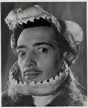 Die Schwarz-Weiß-Fotografie eines Mannes, der eine Tiermaske auf dem Kopf trägt.