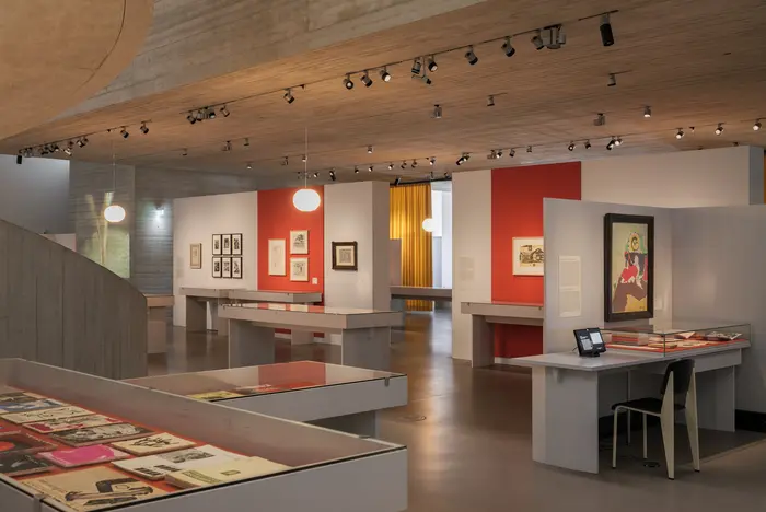 Ein Ausstellungsraum mit massiven Schaukästen und orangefarbenen Wänden.