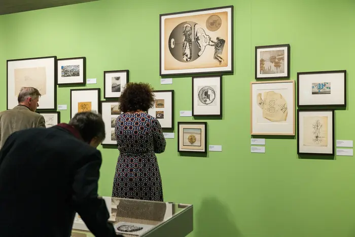 Besuchende in einem Ausstellungsraum mit grünen Wänden.