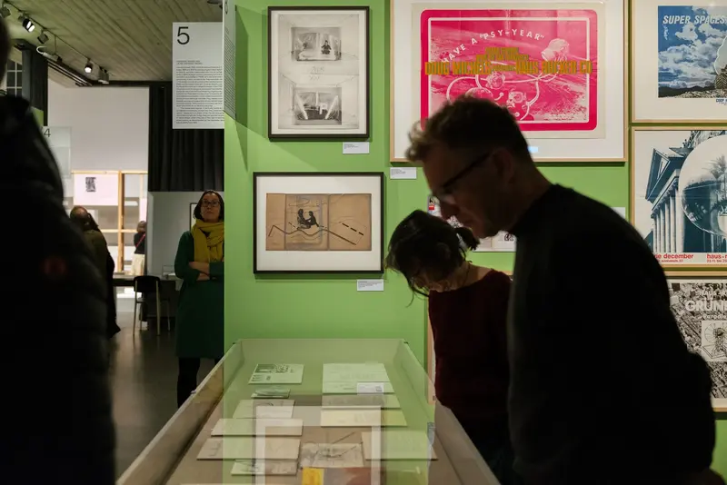 Besuchende in einem Ausstellungsraum mit grünen Wänden.