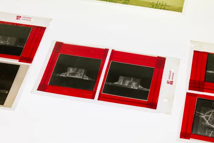 Schwarz-Weiß-Fotografien mit rotem Klebeband auf einer weißen Oberfläche befestigt.