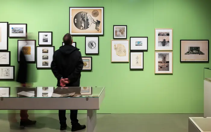 Personen in einem Ausstellungsraum mit grünen Wänden.