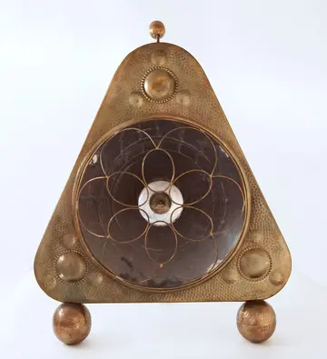 Ein dreieckiger Ofen aus Metall und mit runden Füßen.