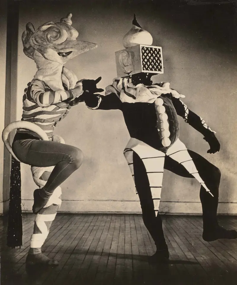 Schwarz-Weiß-Fotografie zweier verkleideter und maskierter Tänzer.