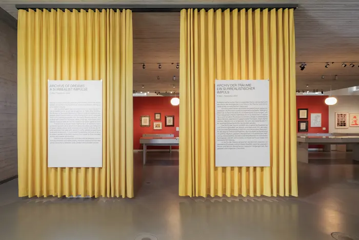 Ein Ausstellungsraum mit zwei gelben Vorhängen.