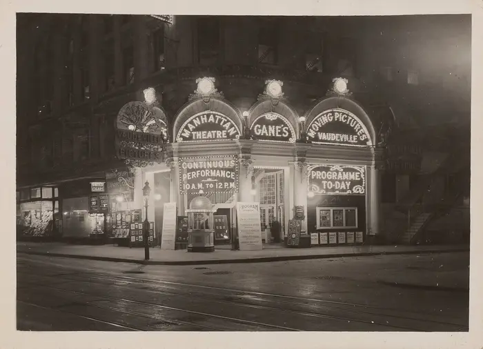 Ein schwarz-weißes Foto zeigt ein Theater in der Nacht. Seine Fassade ist belichtet durch Laterne. 