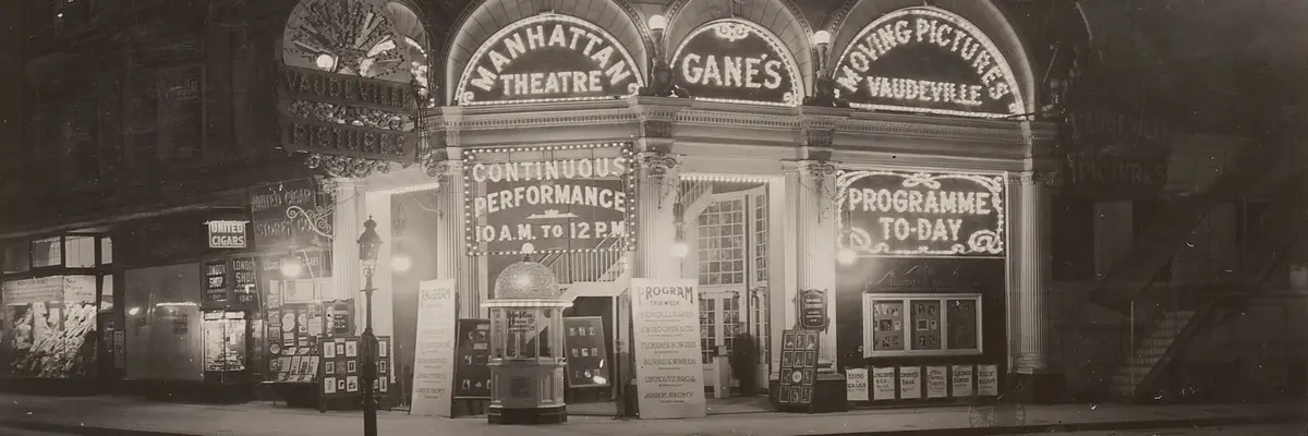 Ein schwarz-weißes Foto zeigt ein Theater in der Nacht. Seine Fassade ist belichtet durch Laterne. 