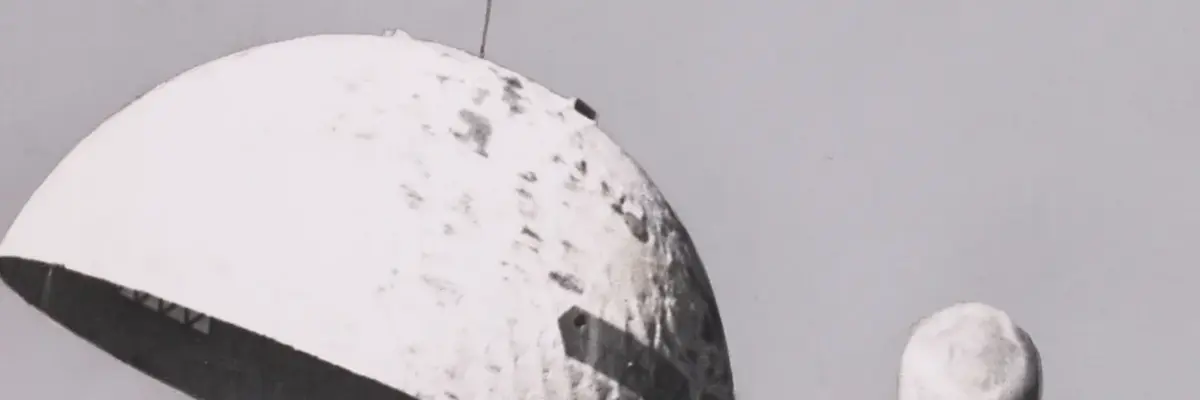 Eine weiße Kuppel wird von einem Hubschrauber vom Boden gehoben.