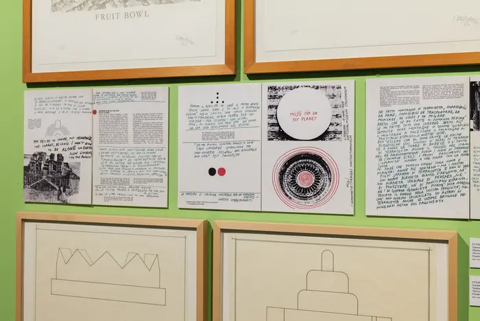 Eine grüne Wand mit gerahmten Kunstwerken.