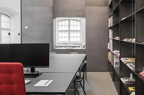 Ein Raum mit Schreibtischen und grauen Wänden.