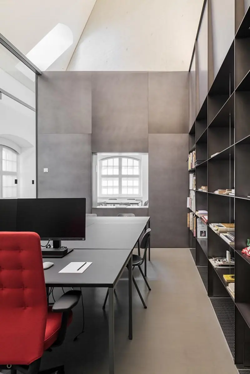 Ein Raum mit Schreibtischen und grauen Wänden.