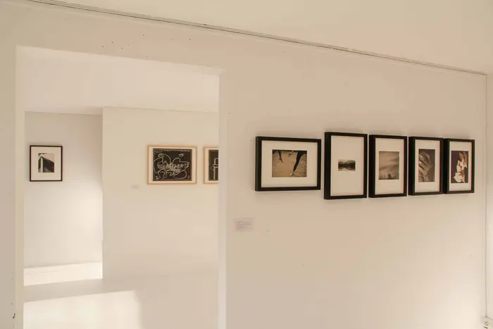 Wände mit in einer Reihe hängenden Bildern in schwarzen Rahmen. 